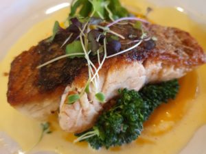 Crispy-skinned barramundi with broccolini on a white plate