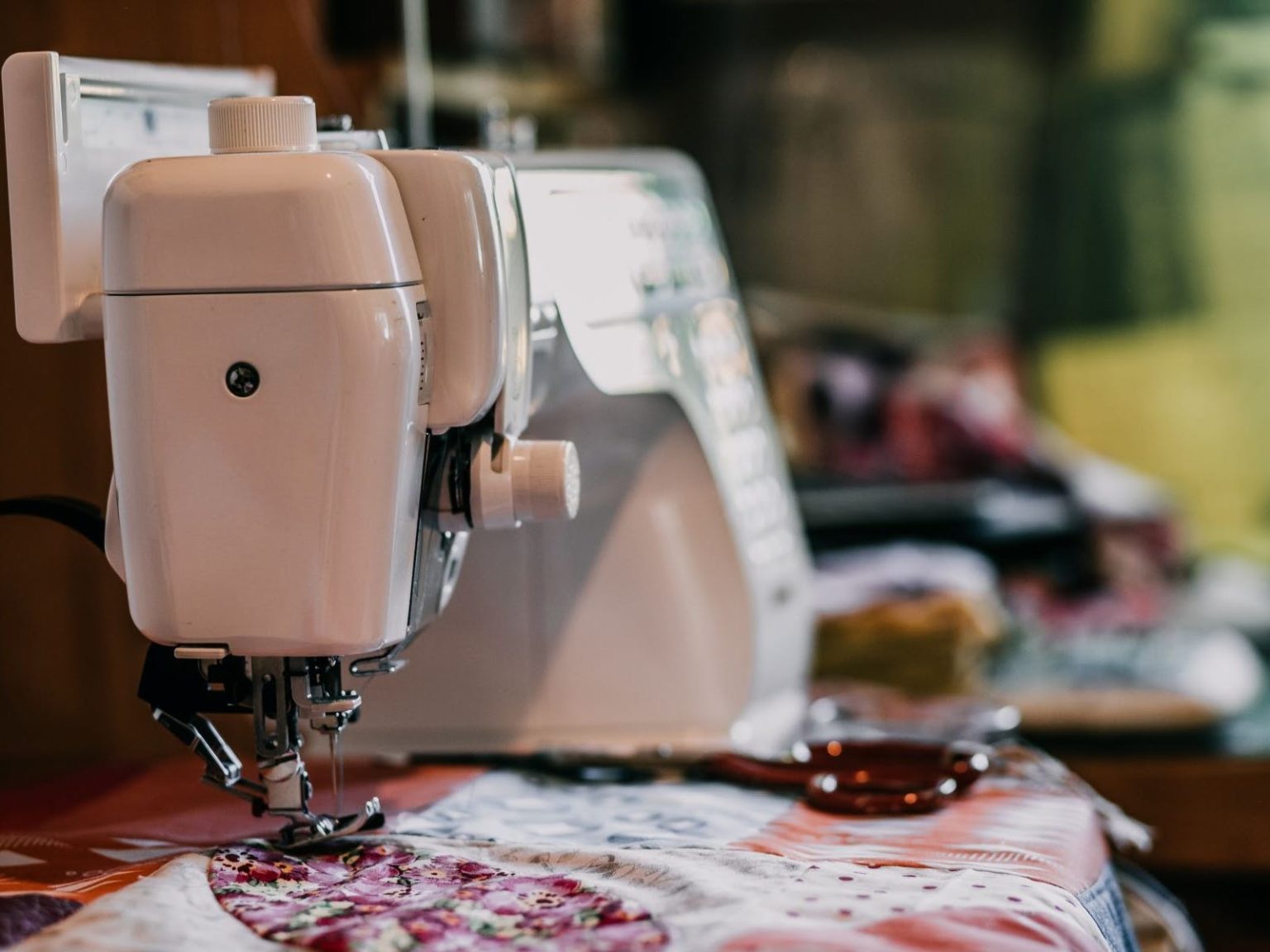 Image of sewing machine  with a pink quilt being sewed