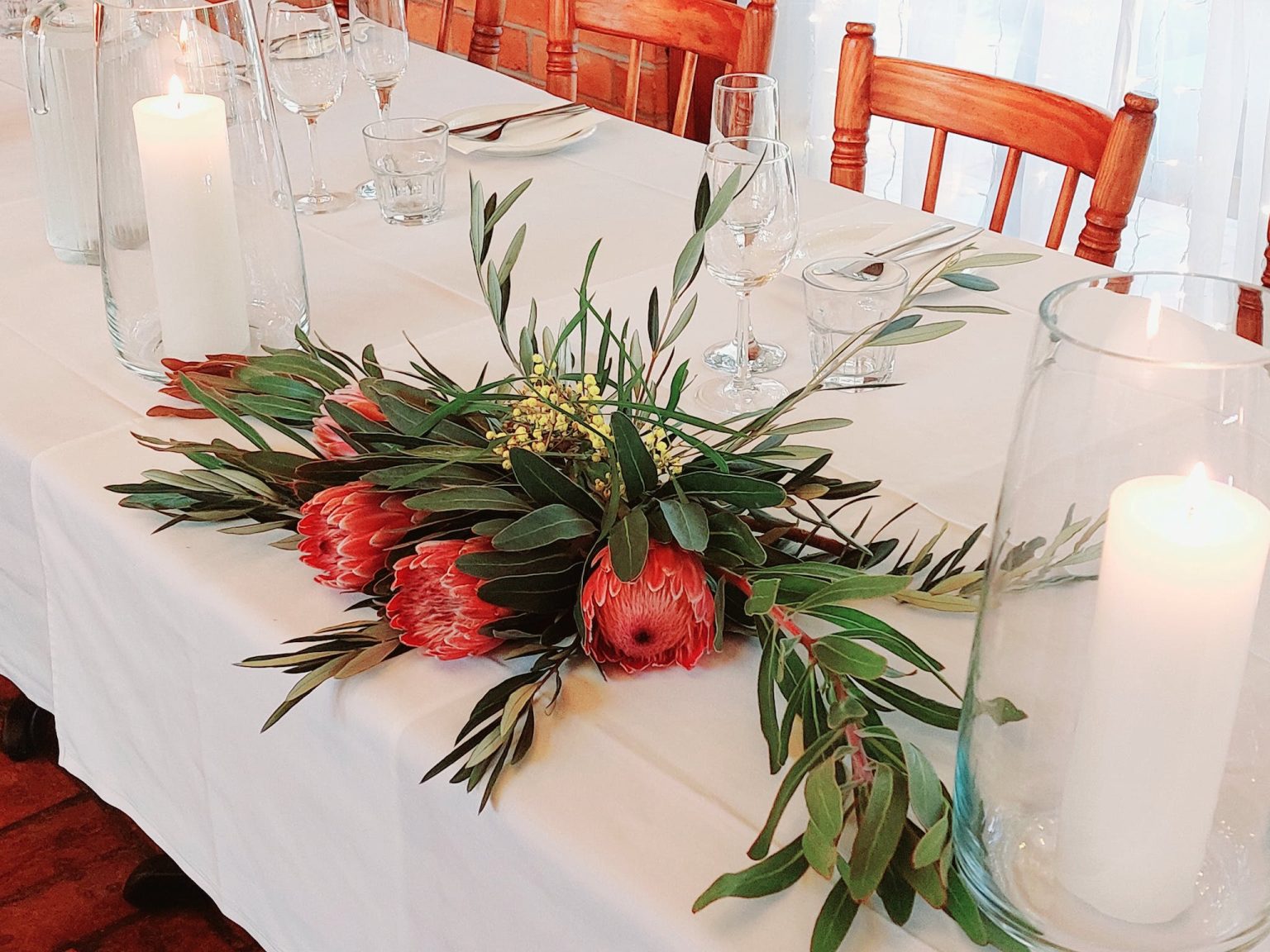 Natife flower arrangement on a white tablecloth with candles