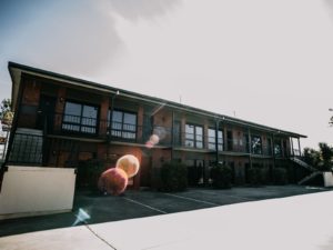Image of double story motel. Sun is shining in the background of image