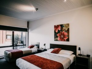 there are two beds in the room with image of red flower hanging on wall behind beds