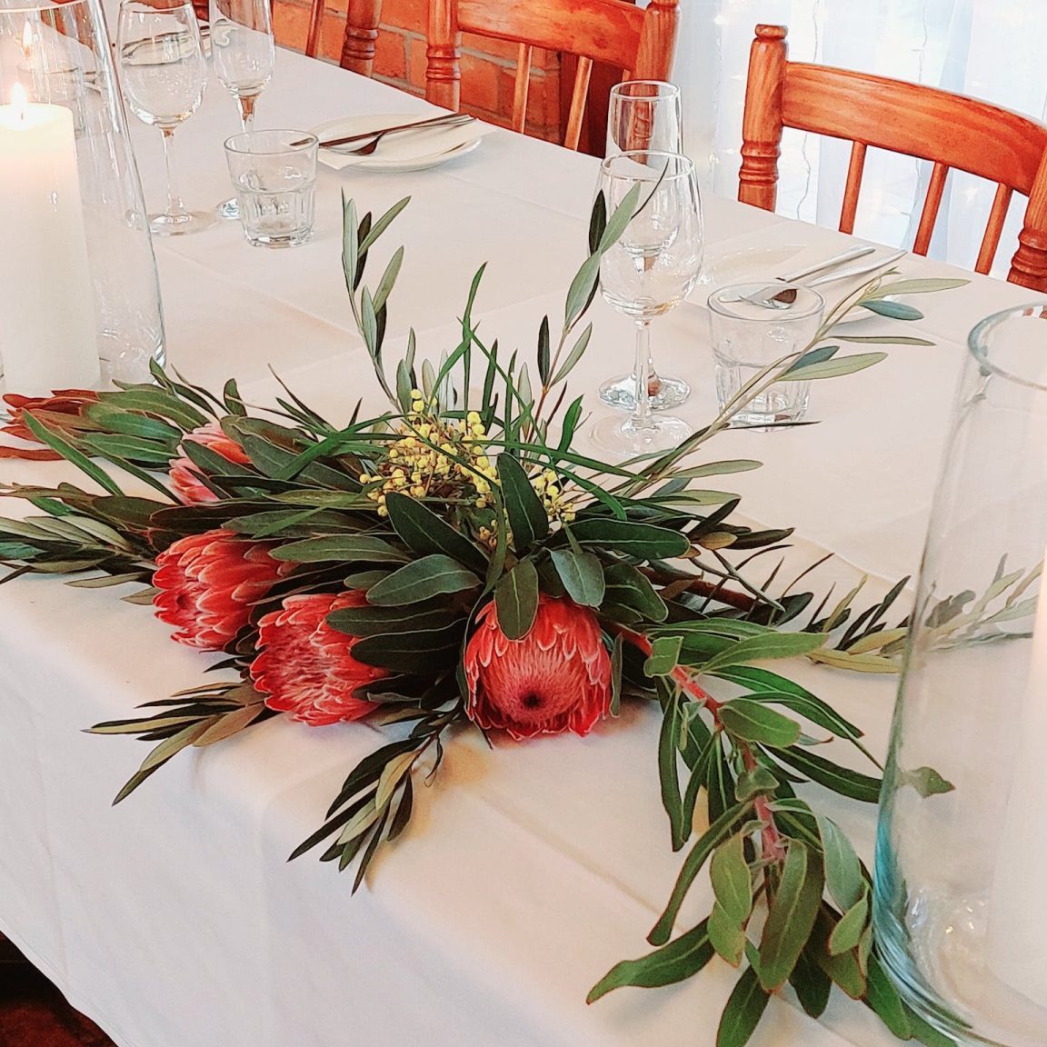 Natife flower arrangement on a white tablecloth with candles